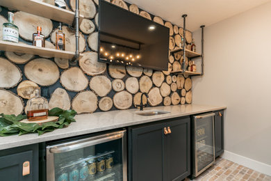 Imagen de bar en casa rústico de tamaño medio con fregadero bajoencimera, armarios con paneles lisos, puertas de armario negras y encimera de cuarcita