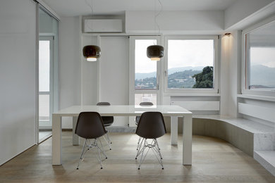 Design ideas for a contemporary separate dining room in Milan with white walls and light hardwood floors.