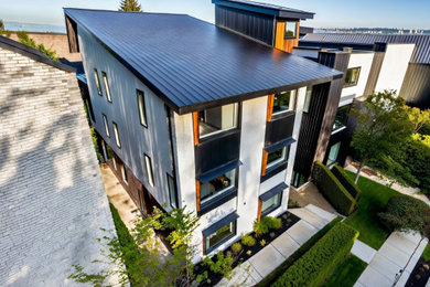 Example of a mid-sized minimalist white three-story mixed siding exterior home design in Vancouver with a metal roof and a black roof