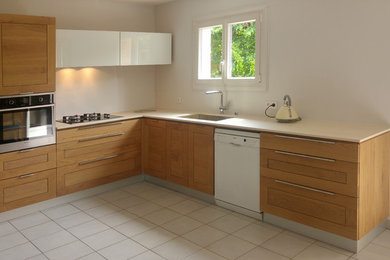 Réalisation d'une cuisine ouverte design en L et bois clair de taille moyenne avec un évier 1 bac, un placard avec porte à panneau encastré, un plan de travail en quartz modifié, un électroménager en acier inoxydable, un sol en carrelage de céramique, aucun îlot et un sol beige.