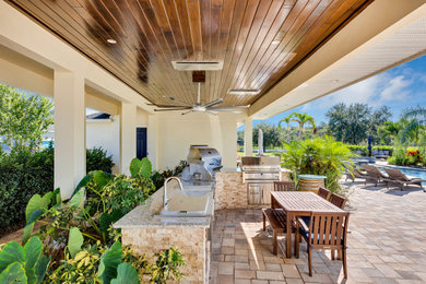 Inspiration for a transitional backyard patio kitchen remodel in Orlando with a roof extension