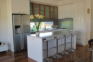 Design ideas for a large modern eat-in kitchen in Melbourne with white cabinets, grey splashback, glass sheet splashback and with island.