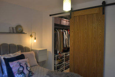 Design ideas for a small modern grey and pink bedroom in Cornwall with white walls, brown floors and feature lighting.