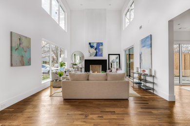 Großes Modernes Wohnzimmer mit weißer Wandfarbe, hellem Holzboden, Kamin, Kaminumrandung aus Stein und braunem Boden in Dallas