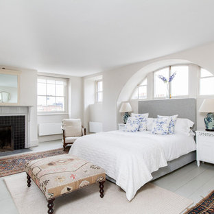 Exemple d'une chambre éclectique avec un mur blanc, un sol en bois peint, une cheminée standard et un manteau de cheminée en carrelage.