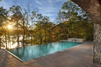 Hot tub - mid-sized tropical backyard rectangular and concrete paver infinity hot tub idea in Other