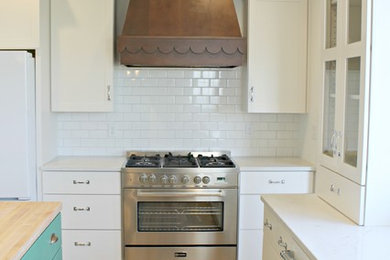 Mid-sized country u-shaped light wood floor and beige floor eat-in kitchen photo in Other with a drop-in sink, flat-panel cabinets, white cabinets, quartz countertops, white backsplash, subway tile backsplash, paneled appliances and an island