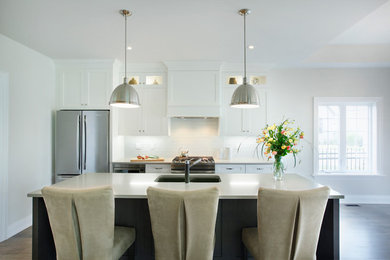 Small transitional single-wall dark wood floor eat-in kitchen photo in Toronto with a double-bowl sink, stainless steel appliances, shaker cabinets, white cabinets, solid surface countertops, white backsplash, an island and glass tile backsplash