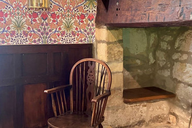 Imagen de comedor de estilo de casa de campo de tamaño medio cerrado con paredes multicolor, suelo de madera oscura, marco de chimenea de piedra, suelo marrón, papel pintado y estufa de leña