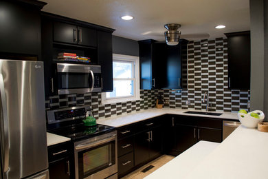 Example of a small minimalist u-shaped ceramic tile and beige floor kitchen design in Oklahoma City with an undermount sink, flat-panel cabinets, black cabinets, quartz countertops, black backsplash, glass tile backsplash, stainless steel appliances and no island