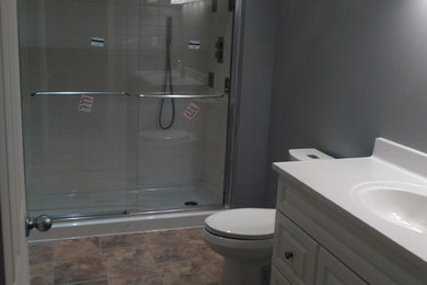 Small minimalist vinyl floor bathroom photo in Toronto with a two-piece toilet, gray walls and an integrated sink