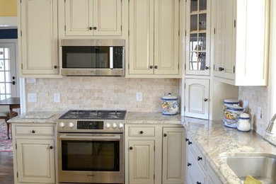 Mid-sized l-shaped medium tone wood floor eat-in kitchen photo in Other with an undermount sink, raised-panel cabinets, white cabinets, granite countertops, beige backsplash, stone tile backsplash, stainless steel appliances and no island