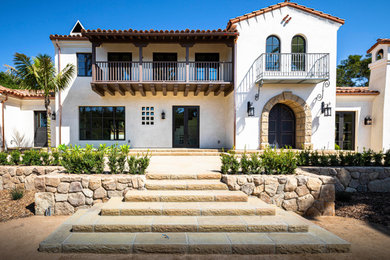 Example of a two-story stucco house exterior design in Santa Barbara with a tile roof and a red roof