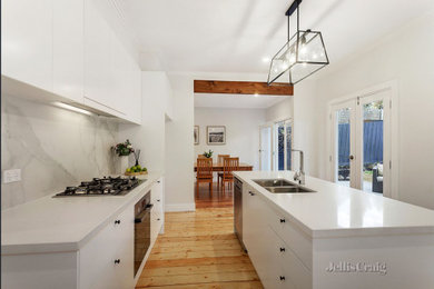 Mid-sized modern galley eat-in kitchen in Melbourne with an undermount sink, flat-panel cabinets, granite benchtops, white splashback, stone slab splashback, stainless steel appliances, medium hardwood floors and with island.