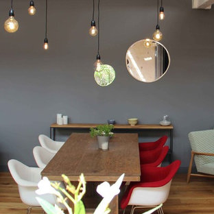 Réalisation d'une salle à manger design avec un mur gris et un sol en bois clair.