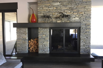 Living room - mid-sized contemporary medium tone wood floor and brown floor living room idea in Other with beige walls, a standard fireplace, a stone fireplace and no tv