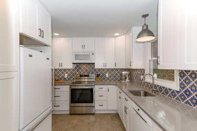 Enclosed kitchen - small transitional u-shaped vinyl floor and brown floor enclosed kitchen idea in Baltimore with an undermount sink, shaker cabinets, white cabinets, quartz countertops, multicolored backsplash, ceramic backsplash, white appliances, no island and gray countertops