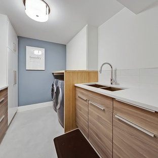 This is an example of a medium sized contemporary galley separated utility room in Calgary with a double-bowl sink, flat-panel cabinets, medium wood cabinets, white walls, a side by side washer and dryer, white floors and white worktops.