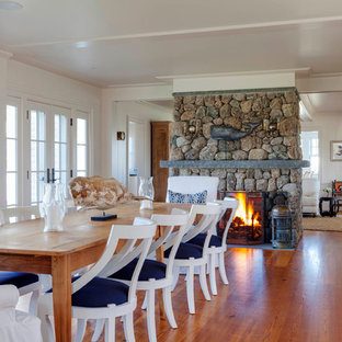 プロビデンスの広いビーチスタイルのLDKの画像 (白い壁、両方向型暖炉、石材の暖炉まわり、淡色無垢フローリング)