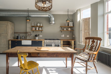 Design ideas for a large industrial single-wall eat-in kitchen in London with a farmhouse sink, no island, open cabinets and stainless steel appliances.