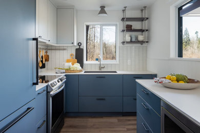 Photo of a small u-shaped separate kitchen in Vancouver with an undermount sink, flat-panel cabinets, blue cabinets, quartz benchtops, white splashback, porcelain splashback, stainless steel appliances, medium hardwood floors, no island, grey floor and white benchtop.