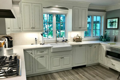 Inspiration for a mid-sized timeless u-shaped porcelain tile and gray floor eat-in kitchen remodel in New York with a farmhouse sink, beaded inset cabinets, white cabinets, quartz countertops, white backsplash, porcelain backsplash, stainless steel appliances, no island and white countertops
