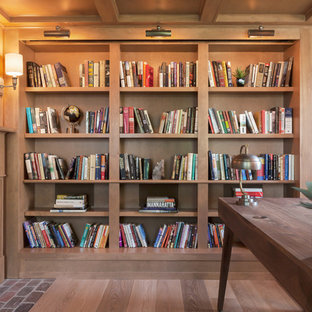 Maritim inredning av ett hemmabibliotek, med mellanmörkt trägolv, en standard öppen spis, en spiselkrans i sten och ett fristående skrivbord