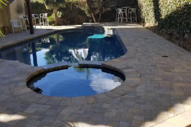 Example of a classic backyard stone and custom-shaped lap hot tub design in Los Angeles