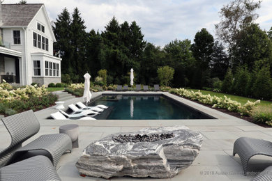 Design ideas for a contemporary backyard rectangular pool in New York with a hot tub and natural stone pavers.