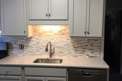 Inspiration for a small eclectic galley enclosed kitchen remodel in Other with a single-bowl sink, recessed-panel cabinets, gray cabinets, quartz countertops, gray backsplash, ceramic backsplash, stainless steel appliances and beige countertops