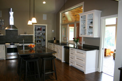 Mid-sized elegant u-shaped medium tone wood floor kitchen photo in Other with an undermount sink, recessed-panel cabinets, white cabinets, quartzite countertops, brown backsplash, stone tile backsplash, stainless steel appliances and an island