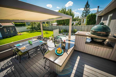 This is an example of a mid-sized transitional courtyard patio in Montreal with an outdoor kitchen, decking and a pergola.