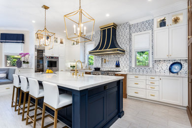 Mid-sized contemporary l-shaped open plan kitchen in Los Angeles with shaker cabinets, white cabinets, marble benchtops, multi-coloured splashback, glass tile splashback, stainless steel appliances, travertine floors, with island, grey floor, white benchtop and a farmhouse sink.
