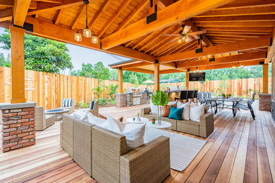 Mid-sized mountain style backyard stone patio kitchen photo with a roof extension