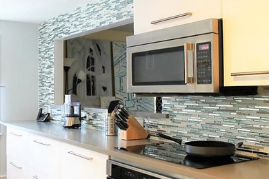 Eat-in kitchen - mid-sized transitional medium tone wood floor and brown floor eat-in kitchen idea in Phoenix with a double-bowl sink, flat-panel cabinets, white cabinets, solid surface countertops, multicolored backsplash, matchstick tile backsplash, stainless steel appliances and no island