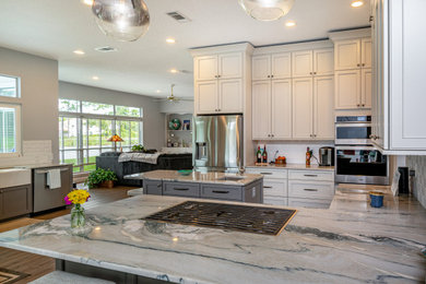 Kitchen - contemporary kitchen idea in Jacksonville with a farmhouse sink, shaker cabinets, white cabinets, white backsplash, stainless steel appliances and an island