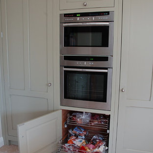 Mid-sized kitchen pantry designs - Inspiration for a mid-sized u-shaped kitchen pantry remodel in Wiltshire with recessed-panel cabinets, green cabinets, granite countertops and an island