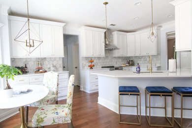 Eat-in kitchen - mid-sized traditional brown floor eat-in kitchen idea in Atlanta with an undermount sink, shaker cabinets, white cabinets, quartz countertops, beige backsplash, stainless steel appliances, a peninsula and white countertops