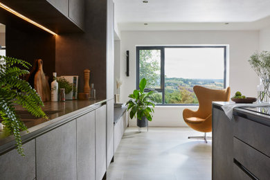Inspiration for a mid-sized modern galley open plan kitchen in Other with a drop-in sink, flat-panel cabinets, solid surface benchtops, mirror splashback, panelled appliances, vinyl floors, with island, grey floor and beige benchtop.