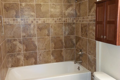 Mid-sized transitional 3/4 porcelain tile and brown floor bathroom photo in Other with furniture-like cabinets, dark wood cabinets, a two-piece toilet, white walls, an integrated sink, quartz countertops and white countertops
