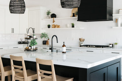 Photo of a large coastal l-shaped kitchen/diner in Phoenix with a single-bowl sink, shaker cabinets, white cabinets, engineered stone countertops, white splashback, metro tiled splashback, stainless steel appliances, light hardwood flooring, an island, beige floors, white worktops and a drop ceiling.