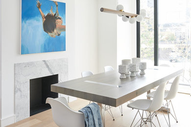 Inspiration for a contemporary light wood floor and beige floor dining room remodel in Toronto with white walls and a standard fireplace