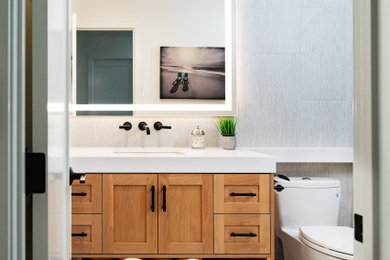 Example of a mid-sized beach style gray tile and porcelain tile porcelain tile and beige floor powder room design in San Diego with shaker cabinets, light wood cabinets, a one-piece toilet, gray walls, an undermount sink, quartz countertops, white countertops and a floating vanity
