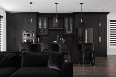Mid-sized minimalist single-wall medium tone wood floor and gray floor eat-in kitchen photo in Toronto with an undermount sink, shaker cabinets, black cabinets, quartz countertops, black backsplash, mosaic tile backsplash, stainless steel appliances, an island and black countertops