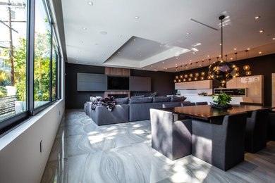 This is an example of a large modern galley open plan kitchen in Los Angeles with flat-panel cabinets, white cabinets, quartz benchtops, white splashback, black appliances, porcelain floors, with island and grey floor.