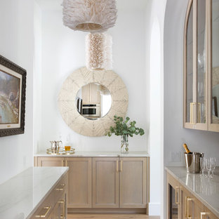 Modelo de bar en casa de galera, mediterráneo, sin pila, con armarios tipo vitrina, puertas de armario de madera clara, suelo de madera clara y encimeras blancas