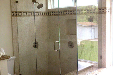 Example of a mid-sized transitional master beige tile and limestone tile limestone floor and beige floor bathroom design in Orange County with black cabinets, a one-piece toilet, beige walls and a hinged shower door