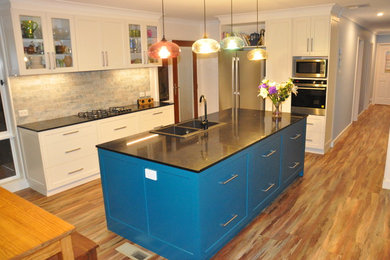 Exempel på ett mellanstort modernt kök, med en dubbel diskho, skåp i shakerstil, turkosa skåp, bänkskiva i kvarts, rostfria vitvaror, mellanmörkt trägolv, en köksö och brunt golv
