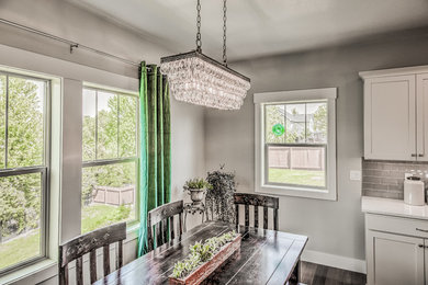 Eat-in kitchen - mid-sized craftsman l-shaped dark wood floor eat-in kitchen idea in Boise with a farmhouse sink, recessed-panel cabinets, white cabinets, quartzite countertops, gray backsplash, glass tile backsplash, stainless steel appliances and an island