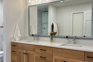 Inspiration for a mid-sized transitional master gray tile and ceramic tile ceramic tile, gray floor and double-sink alcove shower remodel in Other with flat-panel cabinets, medium tone wood cabinets, a two-piece toilet, beige walls, an undermount sink, quartz countertops, a hinged shower door, white countertops, a niche and a built-in vanity